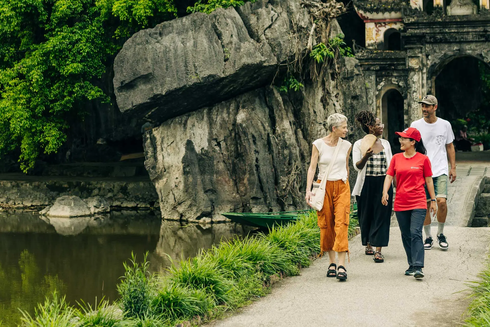 People walking along a bridge next to an ancient temple in Vietnam 